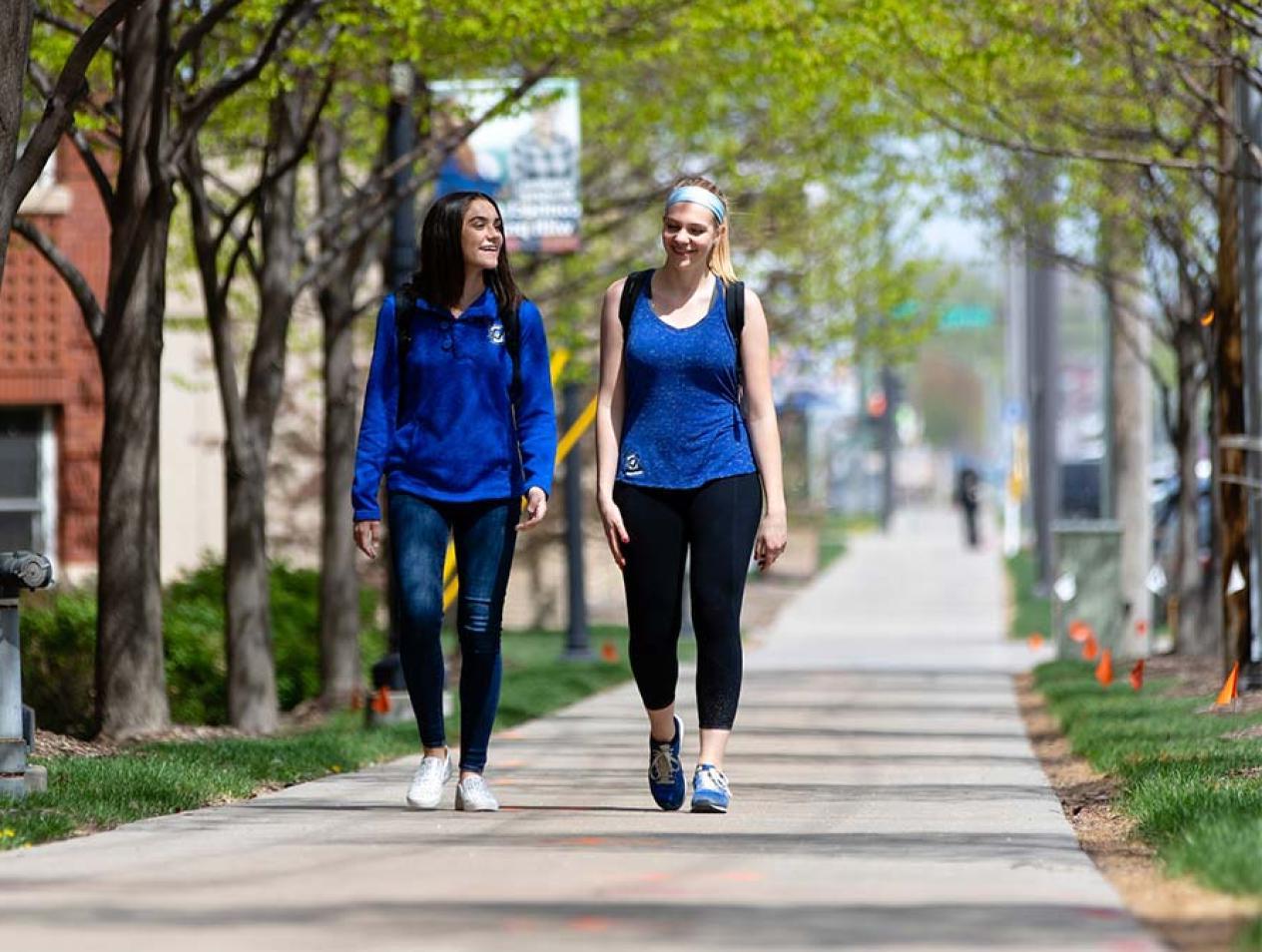 Two students walking on campus in summer